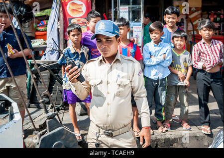 A Cambodian policeman surrounded by street kids attends to a situation in the Cambodian city of Phnom Penh. Stock Photo