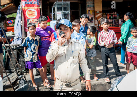 A Cambodian policeman surrounded by street kids attends to a situation in the Cambodian city of Phnom Penh. Stock Photo