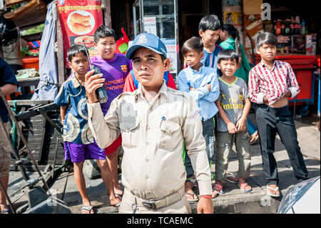 A Cambodian policeman surrounded by street kids attends to a situation in the Cambodian city of Phnom Penh. Stock Photo