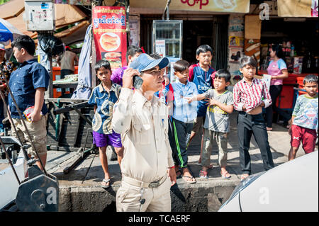 A Cambodian policeman surrounded by street kids attends to a situation in the Cambodian city of Phnom Penh. Stock Photo