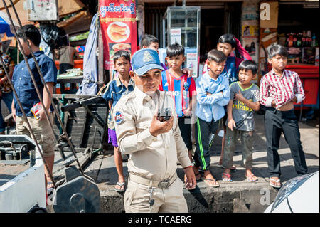 A Cambodian policeman surrounded by street kids attends to a situation in the Cambodian city of Phnom Penh. Stock Photo