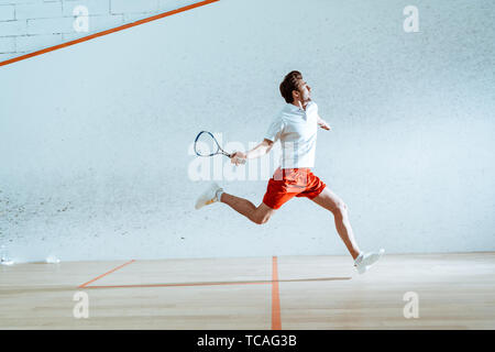 Full length view of sportsman with racket running while playing squash Stock Photo