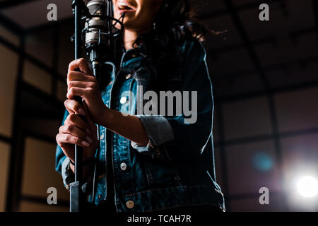 partial view of woman singing near microphone in recording studio Stock Photo