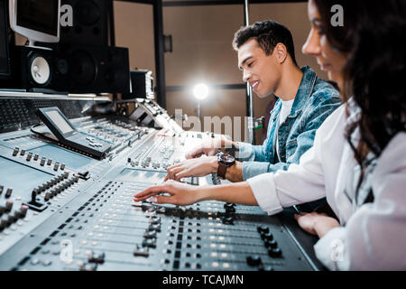 two young multicultural sound producers working at mixing console i recording studio Stock Photo