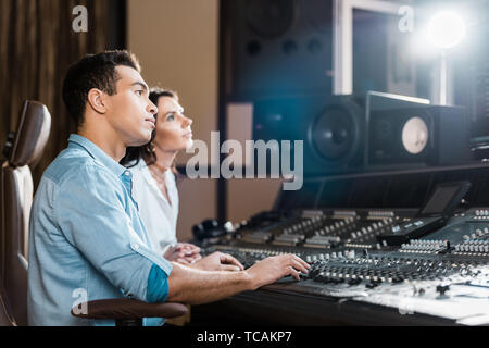 two multicultural musicians working at mixing console in recording studio Stock Photo