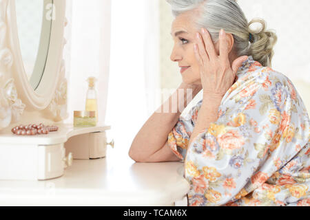 Portrait of happy senior woman sitting near dressing table Stock Photo