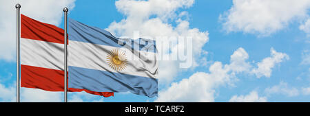 Austria and Argentina flag waving in the wind against white cloudy blue sky together. Diplomacy concept, international relations. Stock Photo