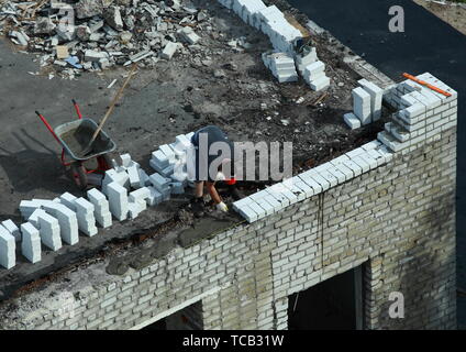 06 05 2019 Russia, Bryansk. The man works on brick and stone construction works. Stock Photo