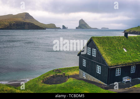 House on the coast of Faroe Islands with Drangarnir sea stack in the background Stock Photo