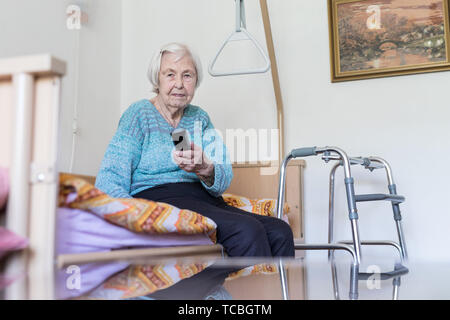 Elderly 96 years old woman operating TV or DVD with remote control Stock Photo