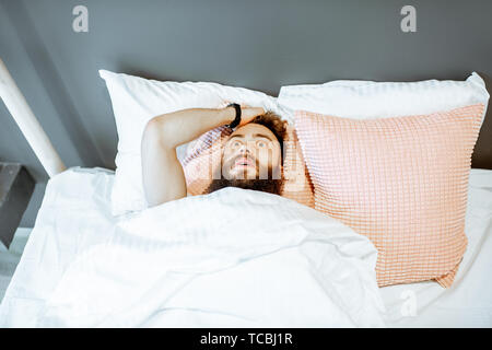 Man feeling stressed lying on the bed, suffering from insomnia or nightmares Stock Photo