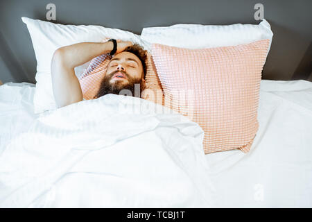 Man feeling stressed lying on the bed, suffering from insomnia or nightmares Stock Photo