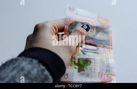 Bank of Scotland £10 note, a tenner, banknote of the pound sterling, May 2019, UK.Woman holding 10 pounds paper Scottish bank note over isolated backg Stock Photo