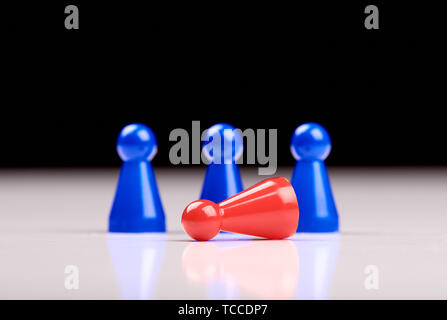 Standing three blue game pieces as winner and lying red figurine as loser on white table top with black background. Space for your text. Stock Photo
