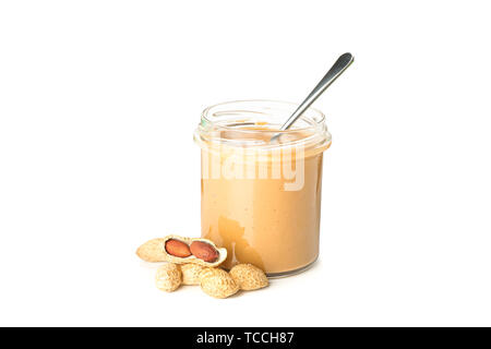 Creamy peanut butter in glass jar, peanut and spoon isolated on white background. A traditional product of American cuisine Stock Photo