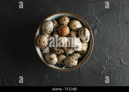 Many quail eggs in bowl on black background, space for text and top view Stock Photo