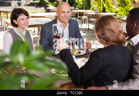 Two happy couples having lunch at open-air restaurant summer Stock Photo