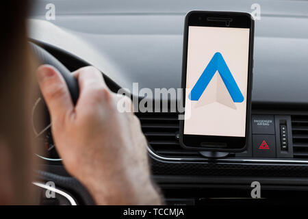 LOS ANGELES, CALIFORNIA - JUNE 6, 2019: Close up to male driving and using navigation appliction Google Android Auto. An illustrative editorial image. Stock Photo