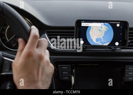 Close up to male driving and using navigation on the smartphone screen. Choose direction, globe on the screen Stock Photo