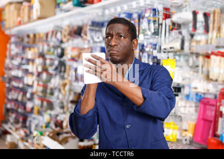 Serious young African American worker taking inventory of goods in building materials store Stock Photo