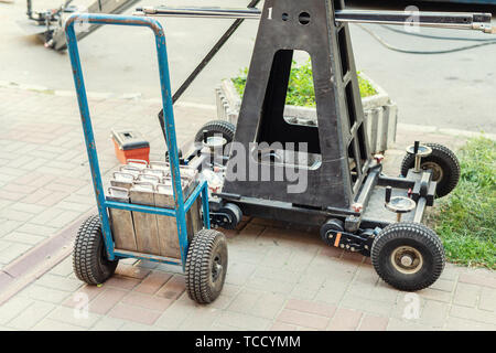 Big camera crane steel counterweight balance. Movie set with professional equipment and media production team on city street. Outdoor film making Stock Photo