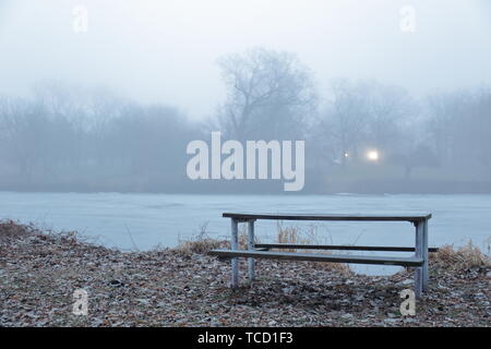 Picnic table at the edge of a river on a gloomy day Stock Photo