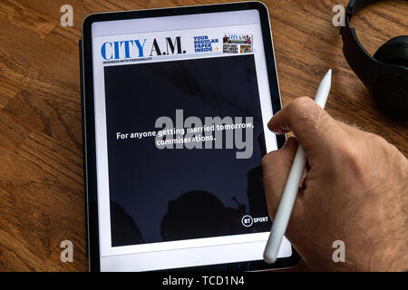 Paris, France - Jun 6, 2019: Man reading on Apple iPad Pro the newspaper with advertising on the first page Stock Photo