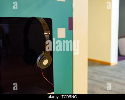 Over ear headphones resting on computer monitor in bright office Stock Photo