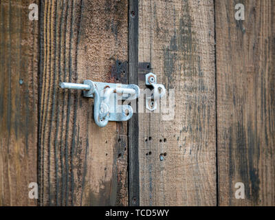 Steel rusty metal latch lock hanging outdoors on wooden double door Stock Photo