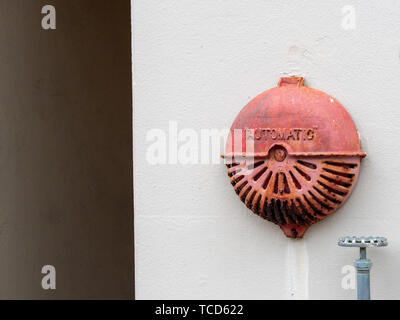 Automatic rusty old fire alarm bell hanging outside of industrial building Stock Photo
