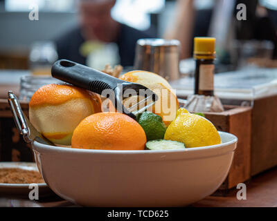Oranges, limes, and lemons for peeling sitting in a bowl on bar to create drinks Stock Photo