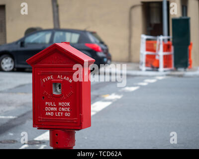 Weathered, old red fire alarm call box on street corner outside  Stock Photo