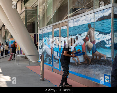 Artist painting mural of ocean and boat at Salesforce Transit Center Stock Photo