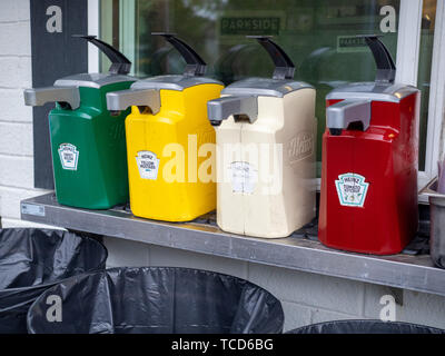 Large commercial dispensers of Heinz ketchup, mustard, relish, and mayonnaise outside for hot dogs and hamburgers Stock Photo