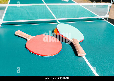 Tennis table with rackets. Bright green table with orange ball and white net. Activities and sports. Banner in a sports shop. The concept of a healthy Stock Photo