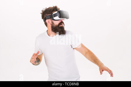 Hipster on scared face exploring virtual reality with modern gadget. Man with beard in VR glasses run away , white background. VR game concept. Guy with head mounted display run in virtual reality. Stock Photo