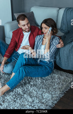 overhead view of handsome man looking at woman gesturing while talking on smartphone Stock Photo