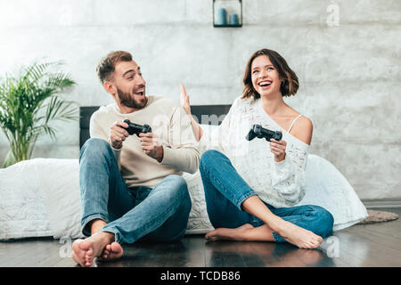 surprised man looking at cheerful woman playing video game at home Stock Photo