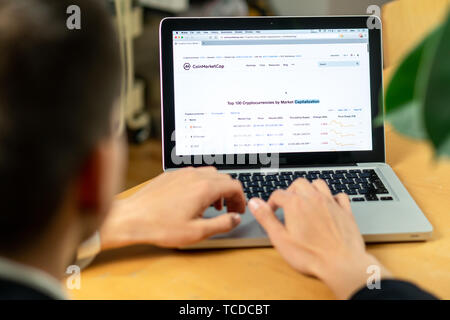 Ljubljana, Slovenia 29.4.2019: businessman sitting at office desk front laptop computers with financial graphs and statistics on monitor website. Stock Photo