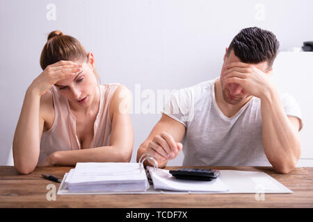 Stressed Young Couple Looking At Invoice On Wooden Desk Stock Photo