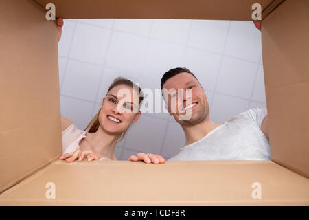 Low Section View Of A Young Happy Couple Looking Inside Cardboard Box Stock Photo