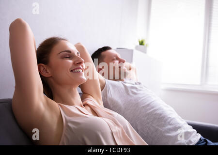 Close-up Of A Happy Young Couple Relaxing On Sofa Stock Photo