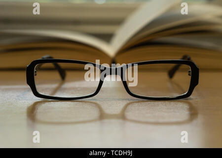 Photo of glasses and opened book behind them, reading concept Stock Photo