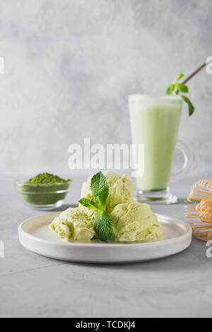 Green matcha ice cream and tea in latte glass on grey table. Close up. Stock Photo