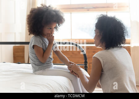 Worried african mother holding hand comforting sad little daughter Stock Photo