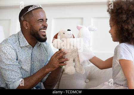 Funny african father wearing crown holding toy playing with daughter Stock Photo