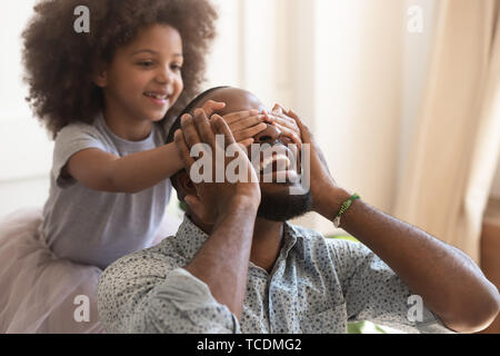 Cute african kid daughter close eyes making surprise for daddy Stock Photo