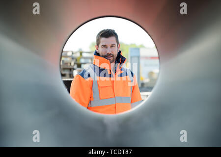 portrait of handsome construction worker framed through round tube Stock Photo
