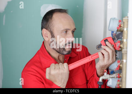 plumber repairing metallic water pipes with wrench Stock Photo