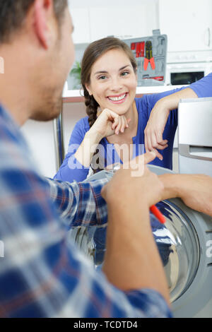 man and woman flirting next to washing machine Stock Photo